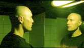 a bald man looks at himself in a mirror