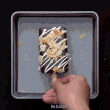 a person is holding a chocolate ice cream bar with almonds and white frosting