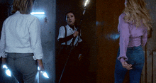 a woman in a purple shirt is holding a torch while standing next to another woman