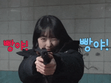 a woman is pointing a gun at the camera with the words " 빵아 " behind her
