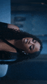 a woman with curly hair is wearing a black dress and earrings