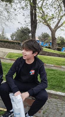 a boy sitting on a bench with a bag that says ' istanbul ' on it