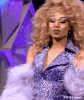 a drag queen is making a kissing face while wearing a blue and silver dress .