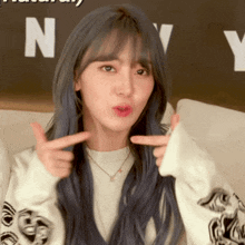 a woman with blue hair is making a funny face with the letter n in the background