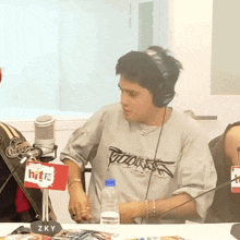 a man wearing headphones is sitting at a table with a sign that says hit on it