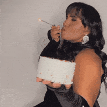 a woman is blowing out a candle on a cake