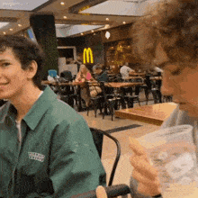 a man wearing a green jacket that says virgil abloh is drinking from a cup
