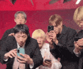 a group of young men are looking at their cellphones