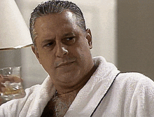 a man in a bathrobe is holding a glass in his hand