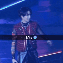 a man in a red jacket stands in front of a microphone with the word kys on the bottom right