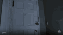 two men standing in a dark hallway with a nbc logo on the bottom right