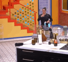 a woman is brushing her teeth in a kitchen with a bottle of wine on the counter