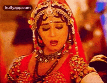 a woman in a red dress and gold jewelry is dancing in a room .