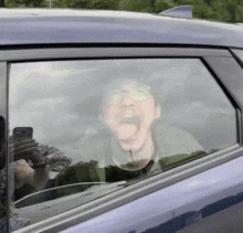 a man in a car with his mouth open and his tongue out