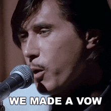 a man singing into a microphone with the words " we made a vow " below him