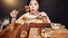 a woman is sitting at a table eating food with chopsticks and a spoon