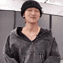 a man wearing a black beanie and a grey jacket with the word magic on the hood