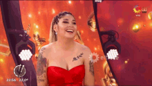 a woman in a red dress is laughing in front of a sign that says vivo