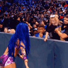 a woman with blue hair is standing in front of a crowd .