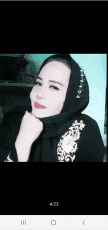 a woman wearing a black hijab with a floral embroidery on the front