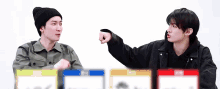 two young men are standing next to each other and one of them is pointing at the other with his fist .