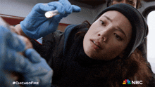 a woman is holding a flashlight in her hand and the nbc logo can be seen in the background