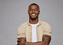 a man with his arms crossed is smiling and wearing a tan shirt