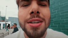 a man with a beard is looking at the camera with his eyes closed and his mouth open .