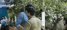 a man in a blue shirt is hugging another man outside