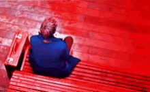 a person is sitting on a red bench with a suitcase