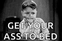 a black and white photo of a sad little boy with the words `` get your ass to bed '' written on it .