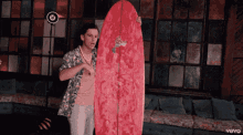 a man is holding a red surfboard that says surf