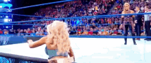 a woman is standing in a wrestling ring with a referee .