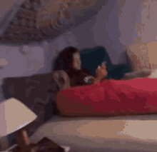 a woman is laying on a couch with a red pillow while looking at her phone .