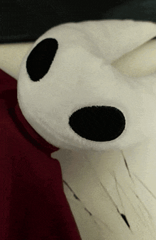 a stuffed animal with black eyes and a red scarf around its neck