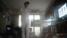 a man is dancing in a living room with a tv in the background .