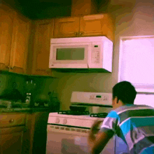 a man in a blue and white striped shirt is in a kitchen