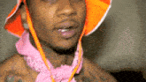 a shirtless man wearing a pink bandana and an orange hat