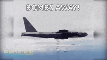 a military plane is flying over a body of water with bombs flying out of it .