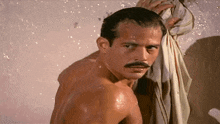 a shirtless man with a mustache is taking a shower and holding a towel over his head