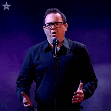 a man singing into a microphone with a star on the bottom right