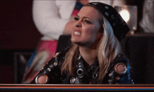 a woman wearing a bandana and a leather jacket makes a funny face