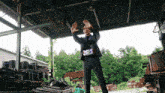 a man in a suit is standing in a warehouse with his hands up in the air
