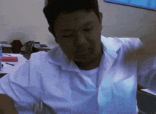 a man in a white shirt is sitting at a table