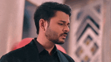 a man with a beard is wearing a black jacket and a black shirt