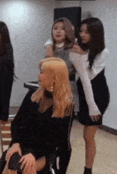 a group of women are standing around a woman sitting in a chair in a room .