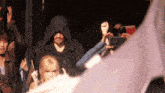 a man in a hooded cloak is surrounded by a crowd of people