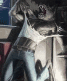 a man is being attacked by a werewolf while wearing a white tank top and jeans .