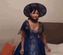 a woman is wearing a blue dress and a hat .