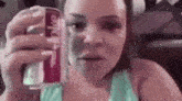 a woman is holding a can of diet coke and making a funny face .